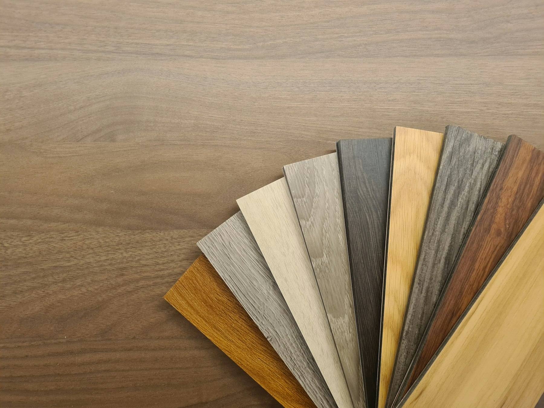 A fan of laminate samples in different wood shades on a table
